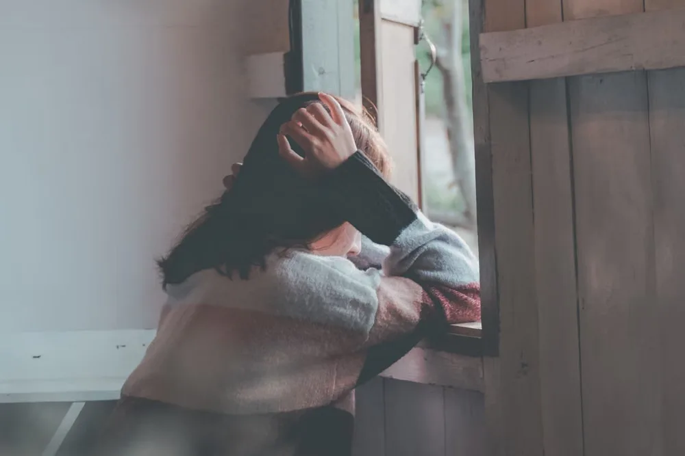 窓の外を見つめながら浮気の疑いを抱える女性