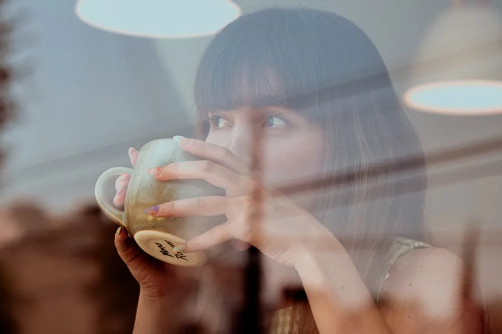 静かなカフェでコーヒーを手に休む女性