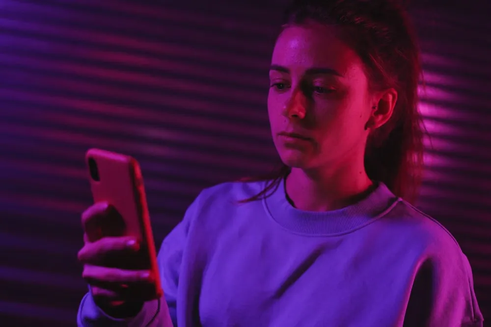 暗がりでスマートフォンを手にする女性