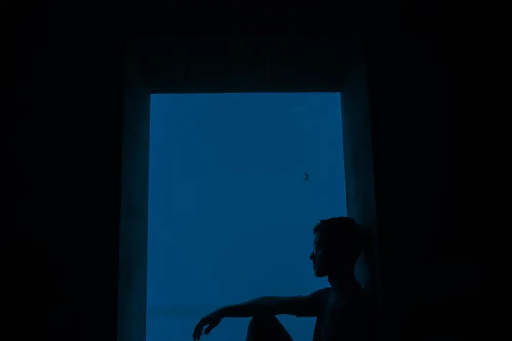 夜の窓辺に座る男性のシルエット