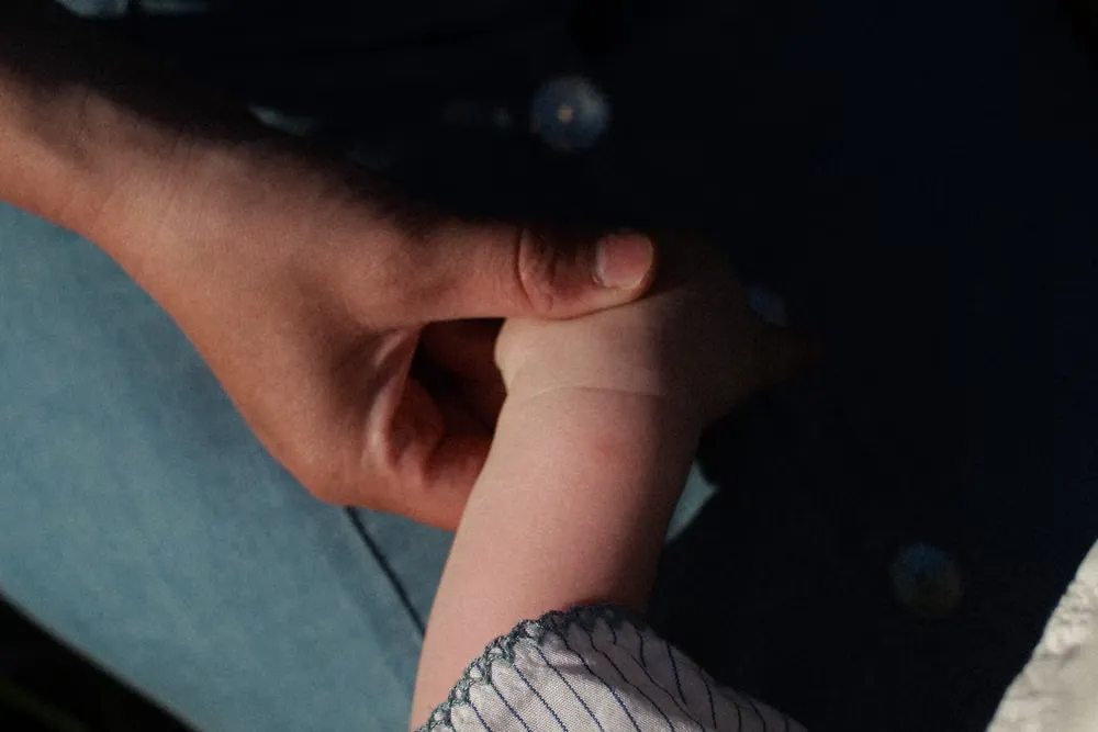 親の手を握る子どもの小さな手
