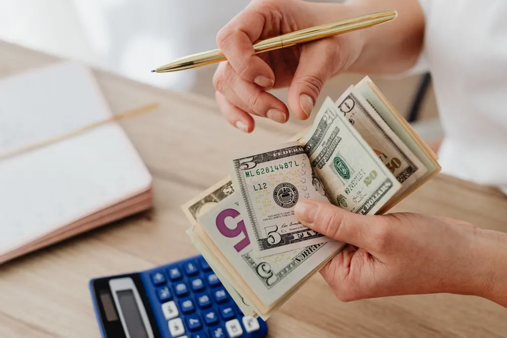 電卓とレシートを前に現金を数える女性