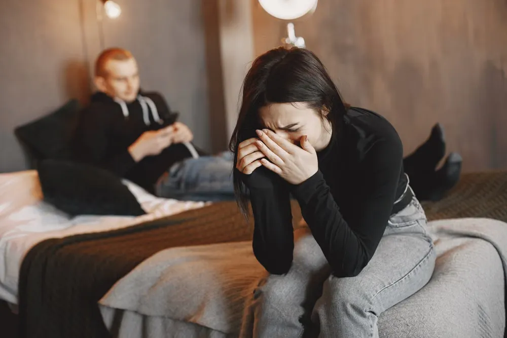薄暗い寝室で背を向け合う夫婦